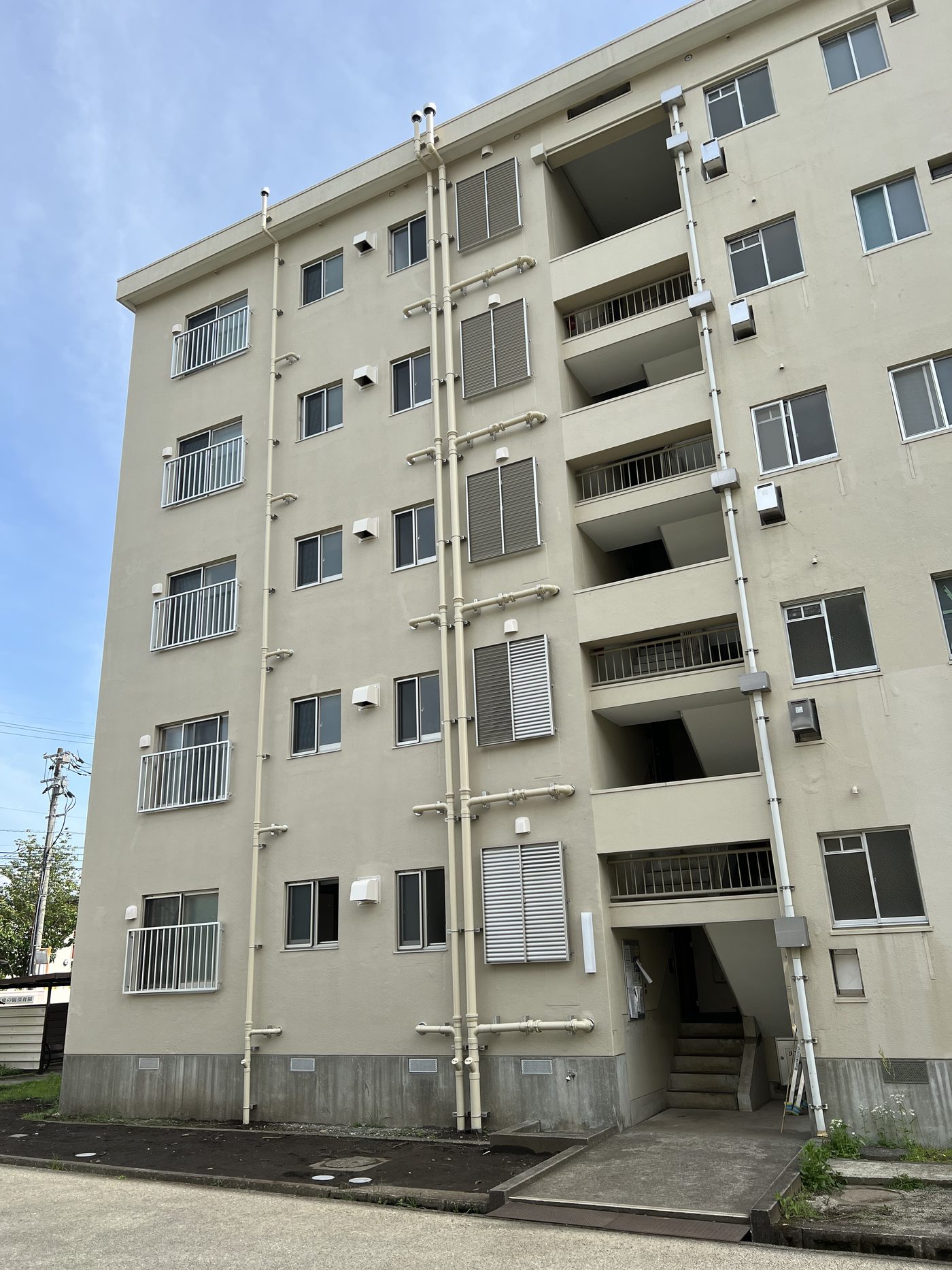 改修後の住棟外観 — 外壁に露出させた配管